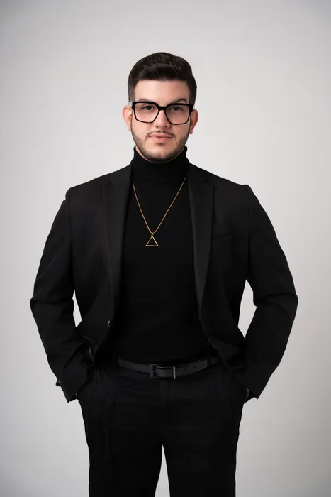 Raed in a black turtleneck and blazer, studio portrait