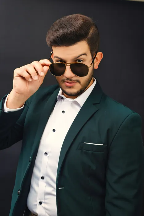 Raed in a green blazer, lowering his sunglasses
